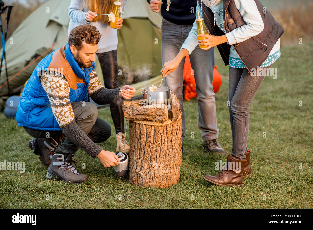 Friends in sweaters eating fondue outdoors Stock Photo