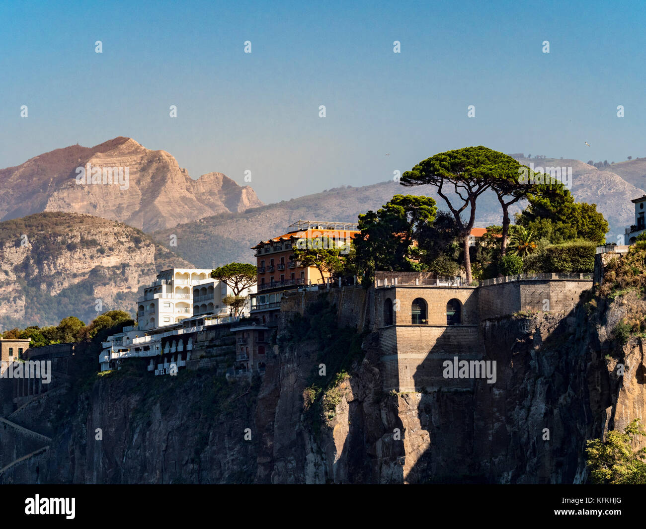 Cliff edge Grand Hotel Riviera with mountain landscape in the background and Stone pine trees in the foreground. Sorrento. Italy. Stock Photo