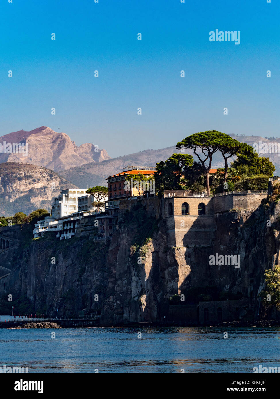Cliff edge Grand Hotel Riviera with mountain landscape in the background and Stone pine trees in the foreground. Sorrento. Italy. Stock Photo