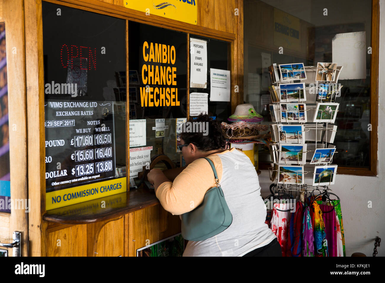 The Seychelles, Praslin, Baie St Anne, jetty, overweight tourist changing money at exchange booth Stock Photo