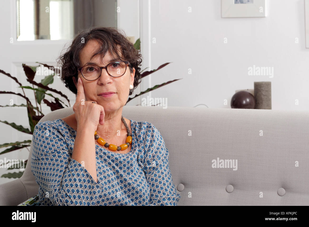 a portrait of mature woman sitting on her sofa Stock Photo - Alamy