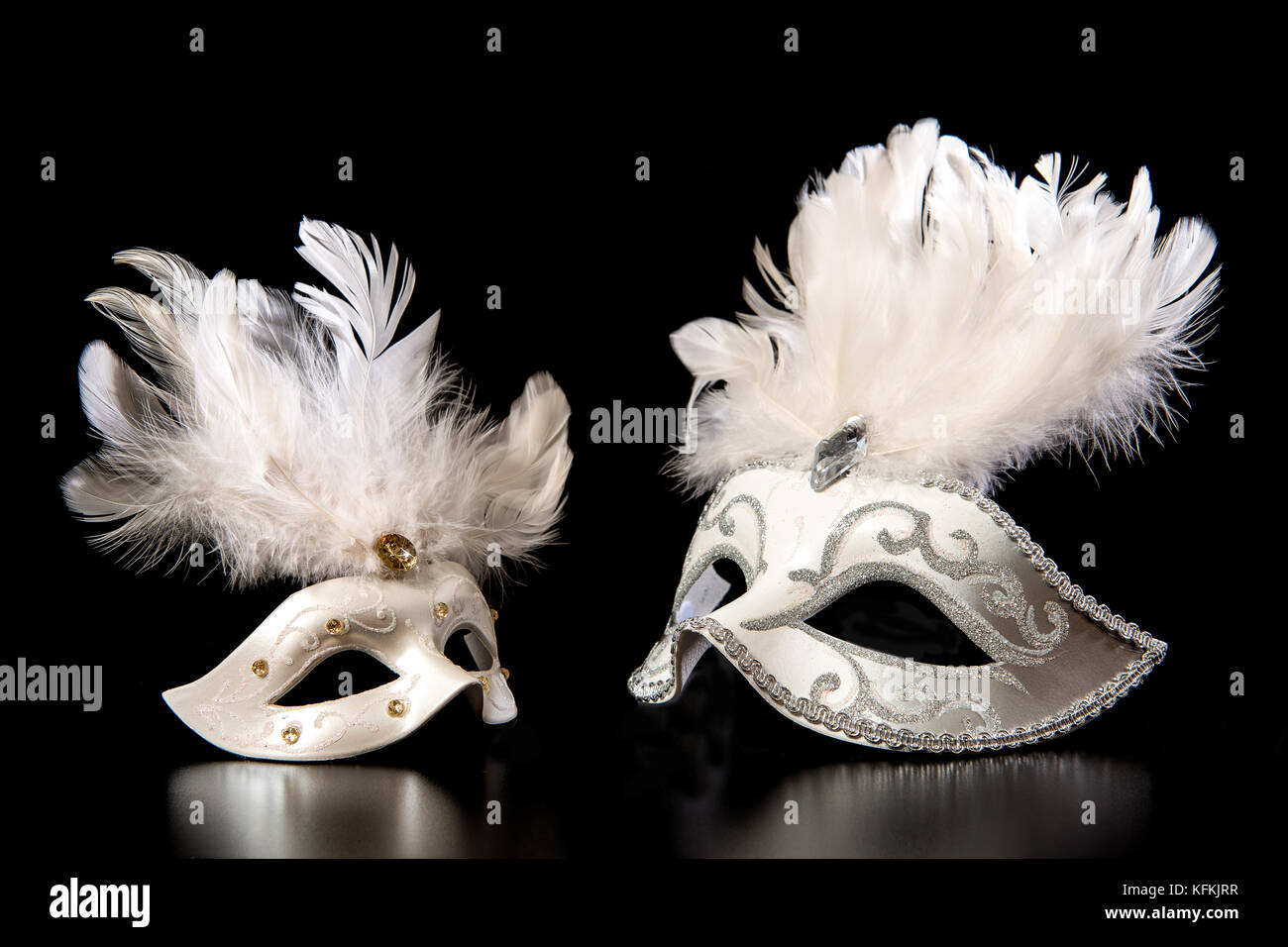 Pretty white venician golden carnival masks with feathers isolated on a mysterious black background Stock Photo