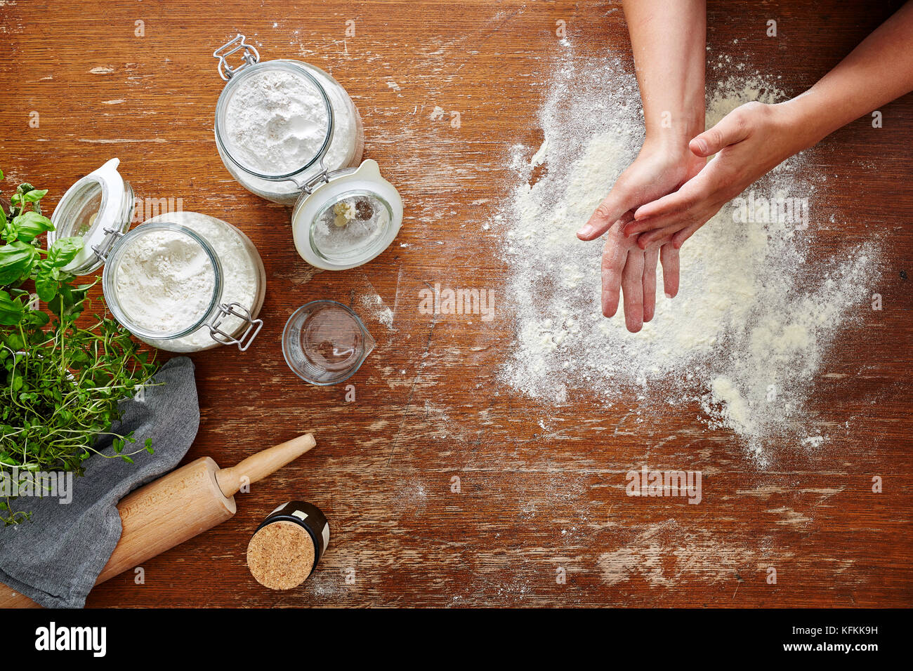 hands dusting off flour baking scene flour on wooden table Stock Photo