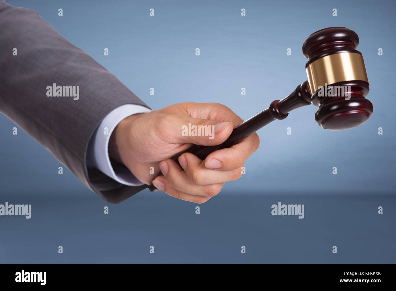 Hand holding judge mallet over blue background Stock Photo