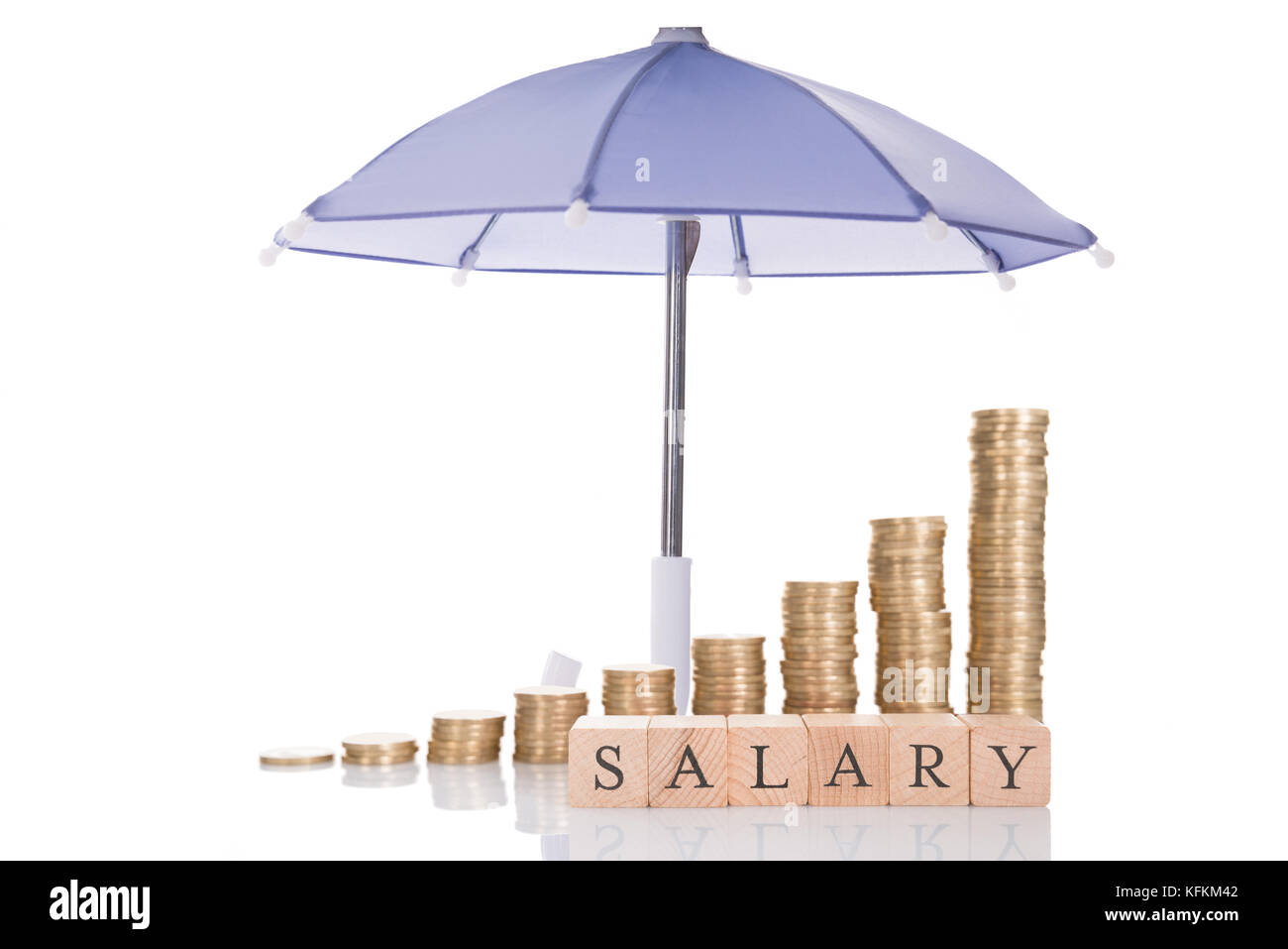 Stacked coins and salary blocks under umbrella isolated over white