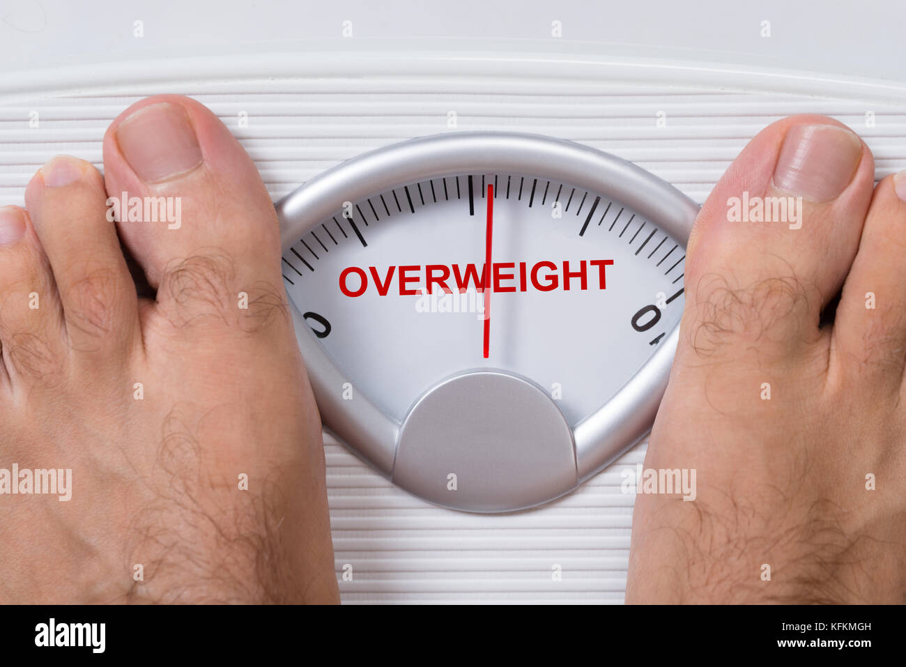 Closeup of man's feet on weight scale indicating Overweight Stock Photo