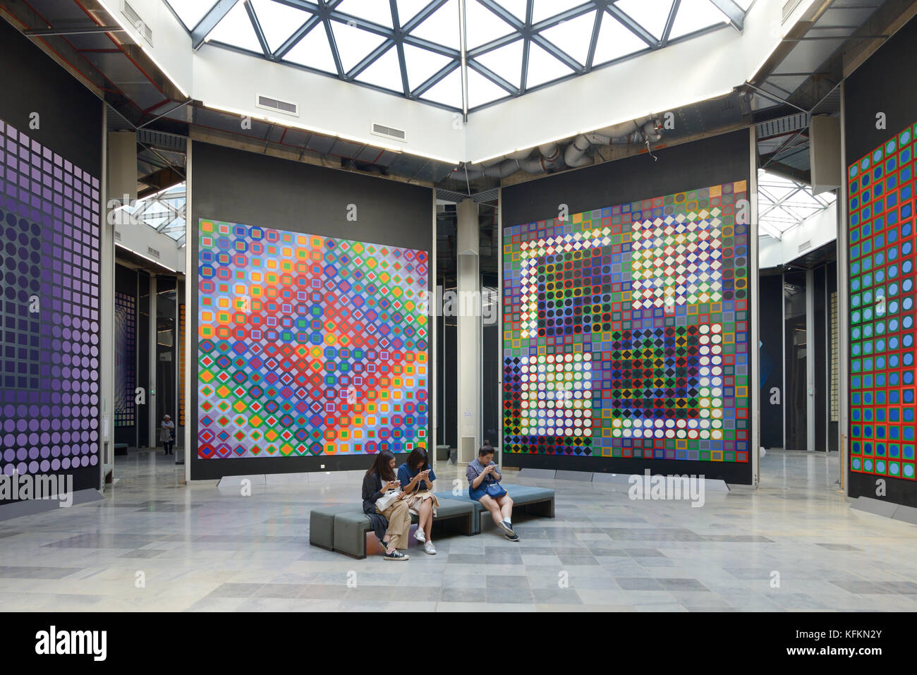 Asian Visitors Consult Smartphones in Art Gallery Interior in the Vasarely Foundation or Fondation Vasarely Museum, Aix-en-Provence, Provence, France Stock Photo