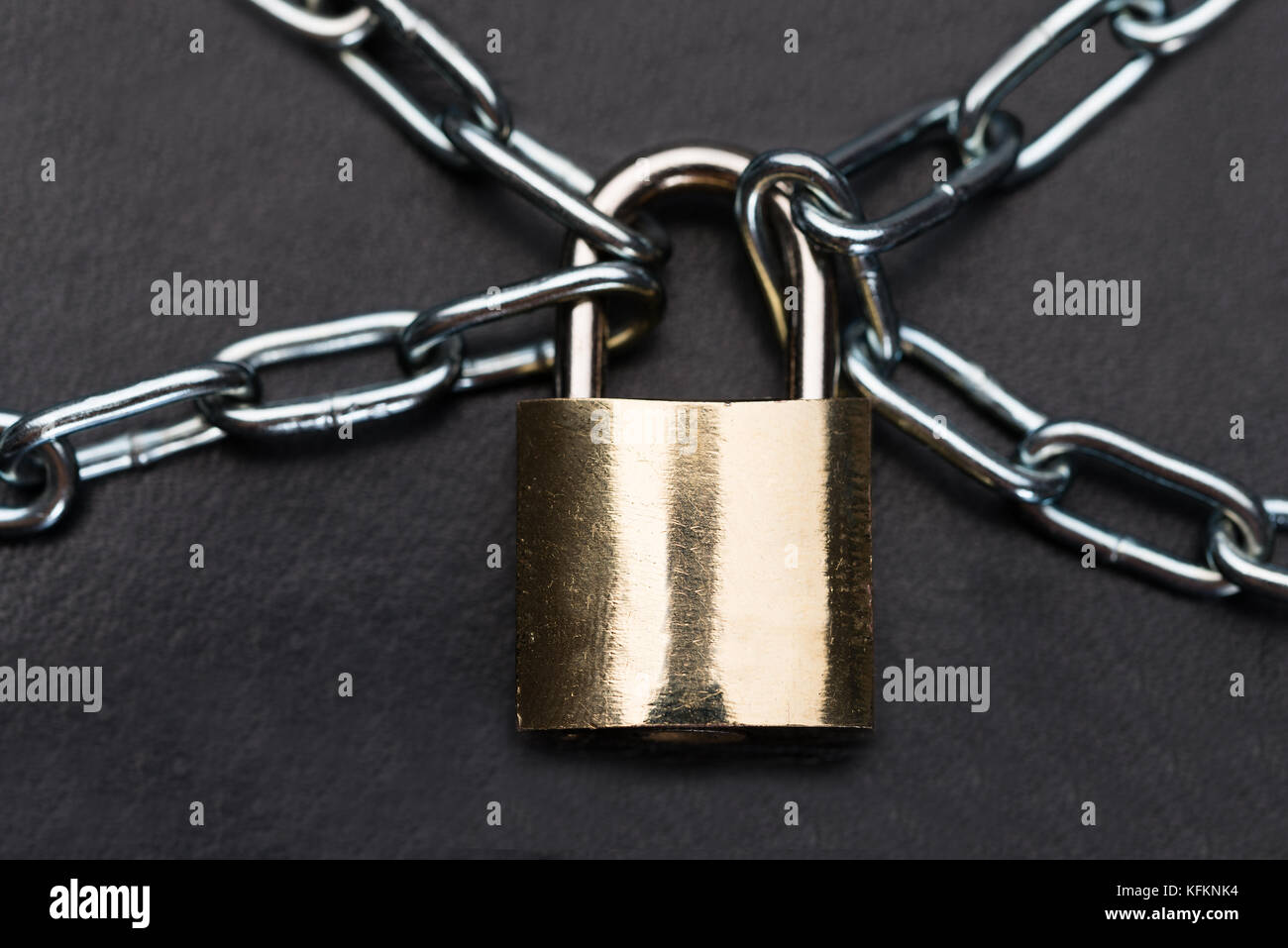 Closeup of metallic padlock and chains isolated over black background ...