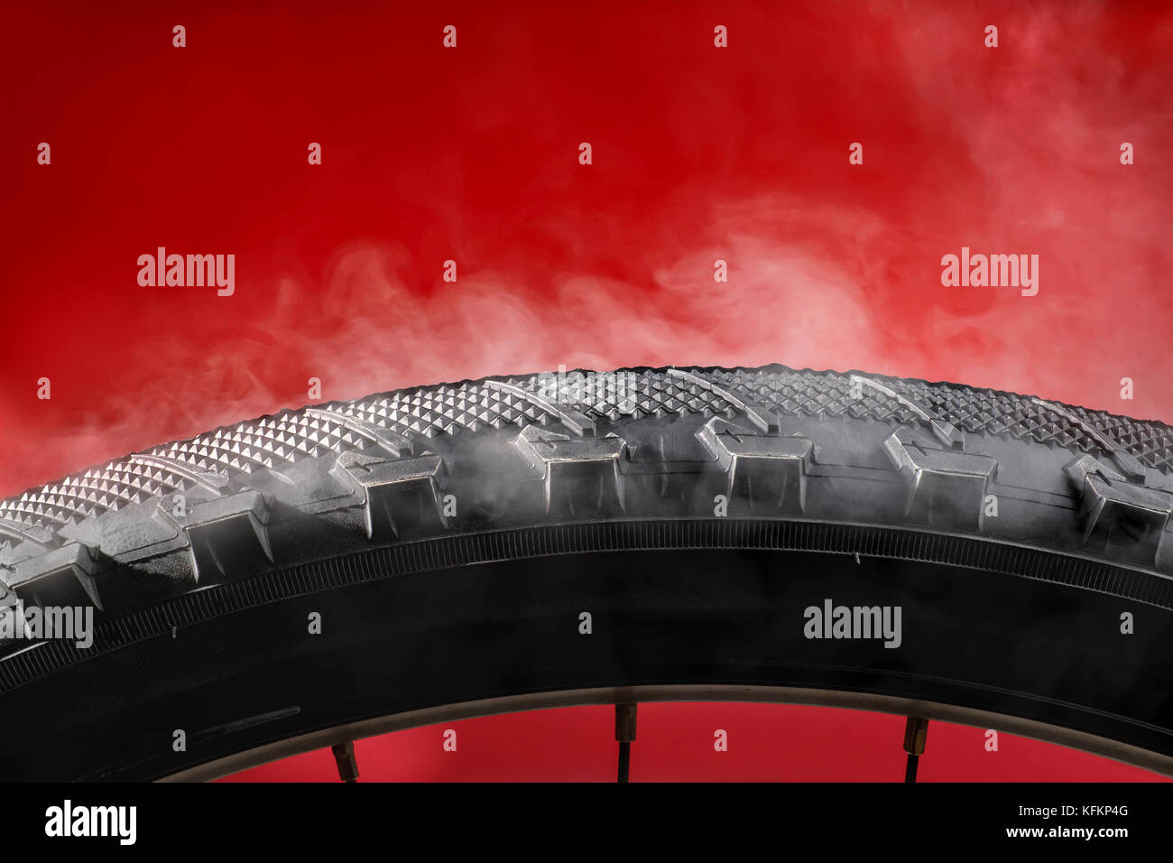 Smoking bike tire. On red background Stock Photo - Alamy