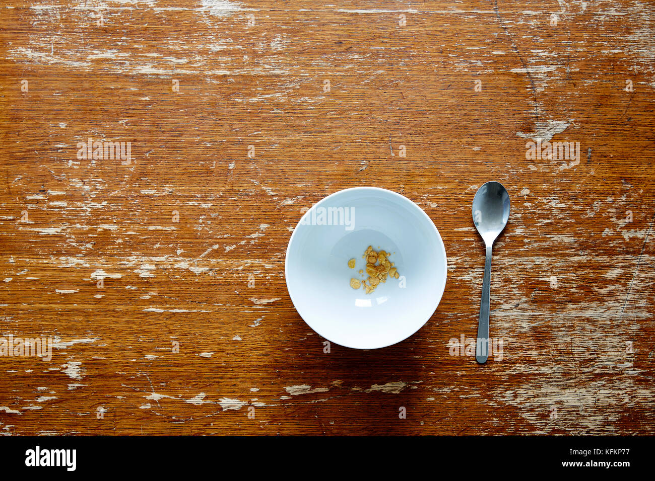empty bowl with little cereal on dark wooden table Stock Photo - Alamy