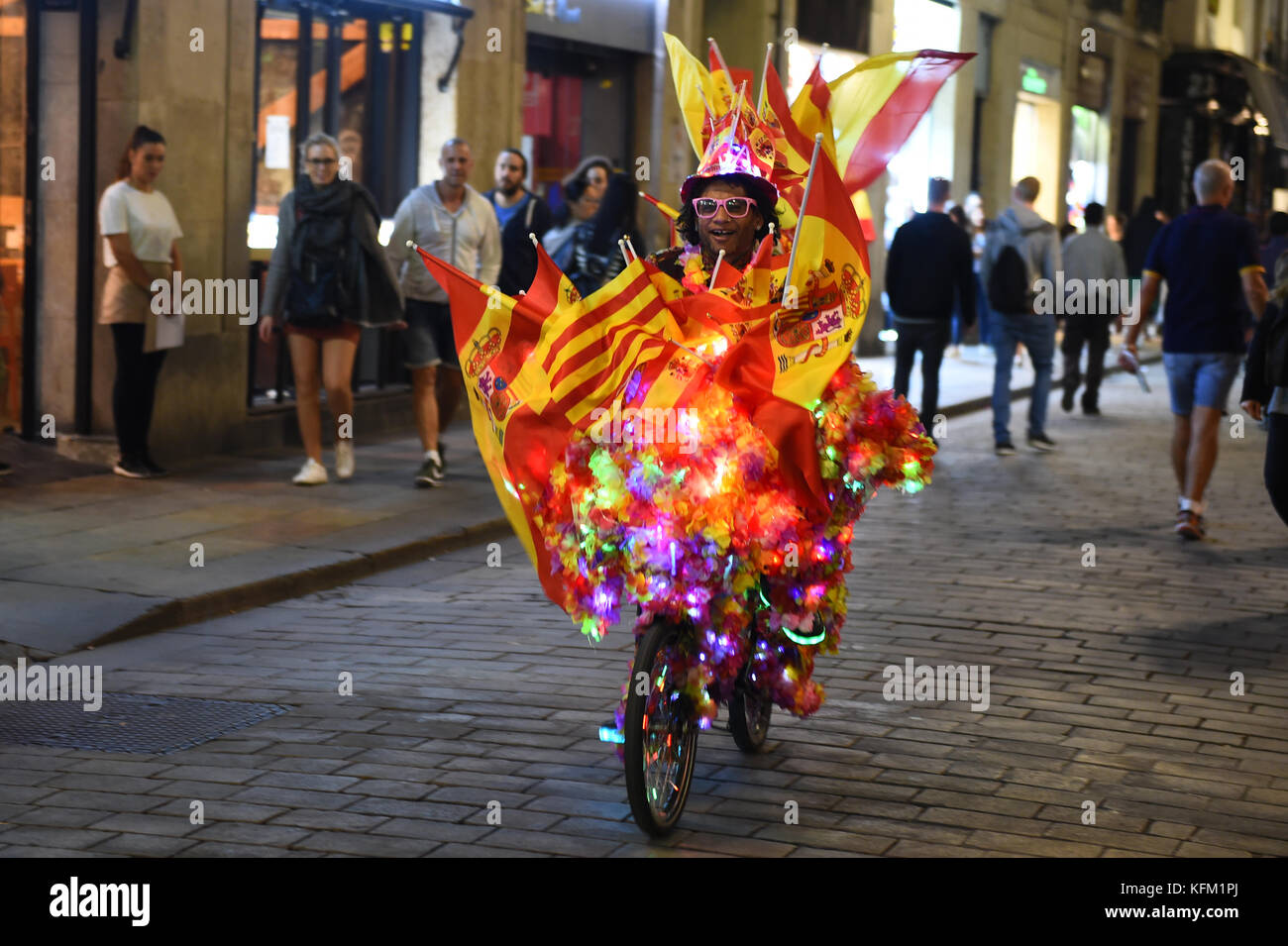 The light artist Jamal drives on his colourfully decorated bicycle with Spanish flags across Barcelona, 29 Octoebr 2017. Jamal, who is of Jamaican origin, attached several paper flowers, chain of lights and Spanish flags to his bike and drives around the streets in the night time. 'This is my personal demonstration for the unity of Spain', says Jamal. Photo: Andrej Sokolow/dpa Stock Photo