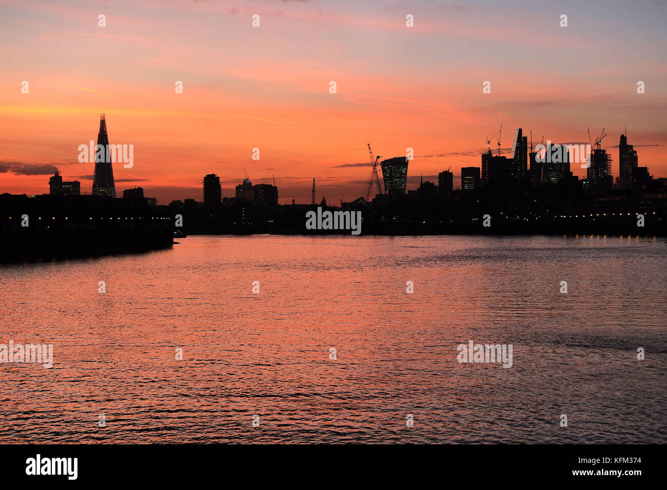 London, UK. 30th October, 2017. The stunning sunset across the City of London high lighting the iconic buildings that have sprung up in London recently and the vast amount of construction tower cranes creating even more skyscrapers. The photo is taken from the river bank at Canary Wharf. Credit: Nigel Bowles/Alamy Live News Stock Photo