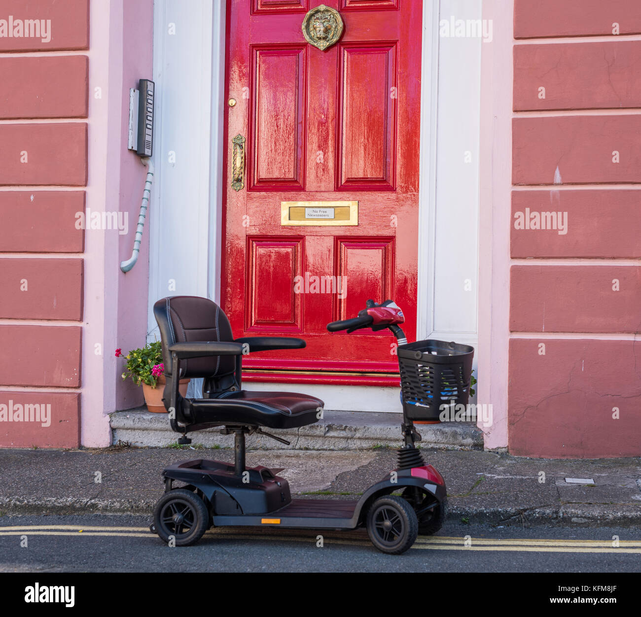 Mobility Scooter parked on yellow lines outside house. Stock Photo