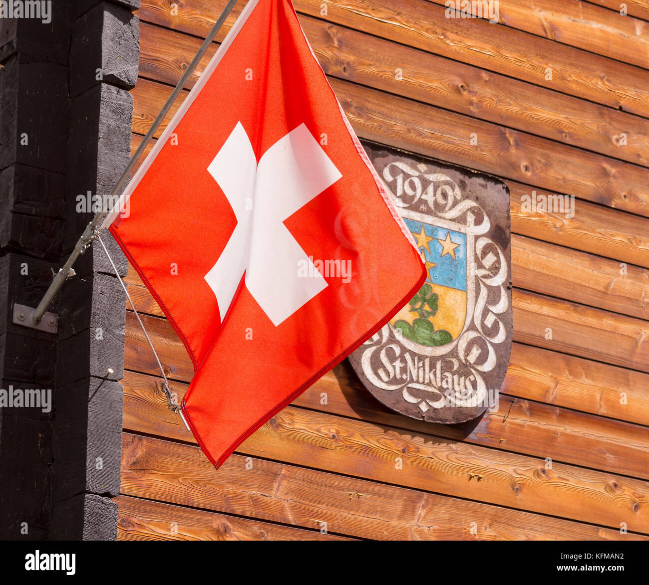 ST. NIKLAUS, SWITZERLAND - Swiss flag and St. Niklaus sign on wooden wall. Stock Photo