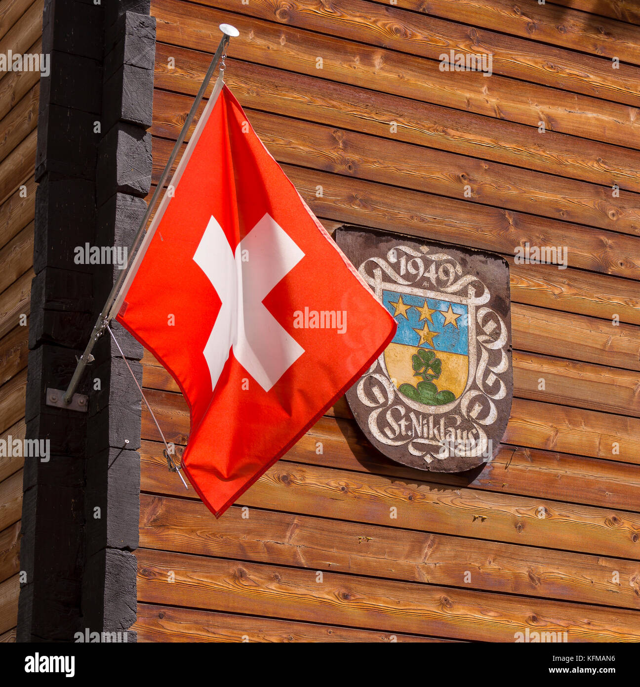 ST. NIKLAUS, SWITZERLAND - Swiss flag and St. Niklaus sign on wooden wall. Stock Photo