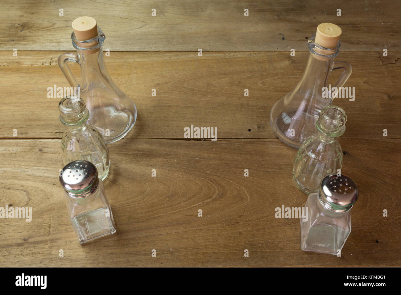 Olive oil, vinegar glass bottles, salt and pepper shakers set on wooden