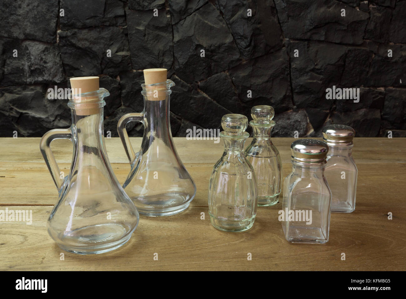 Olive oil, vinegar glass bottles, salt and pepper shakers set on wooden