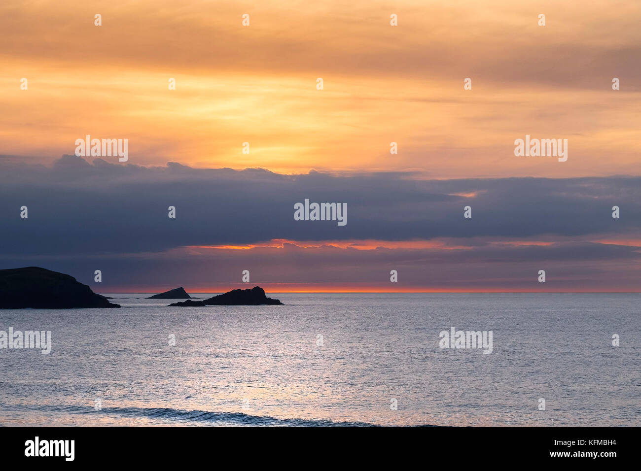 Spectacular sunset - The Goose and The Chick small islands off East Pentire Headland are seeen in silhouette as the sun sets over Fistral in Cornwall. Stock Photo