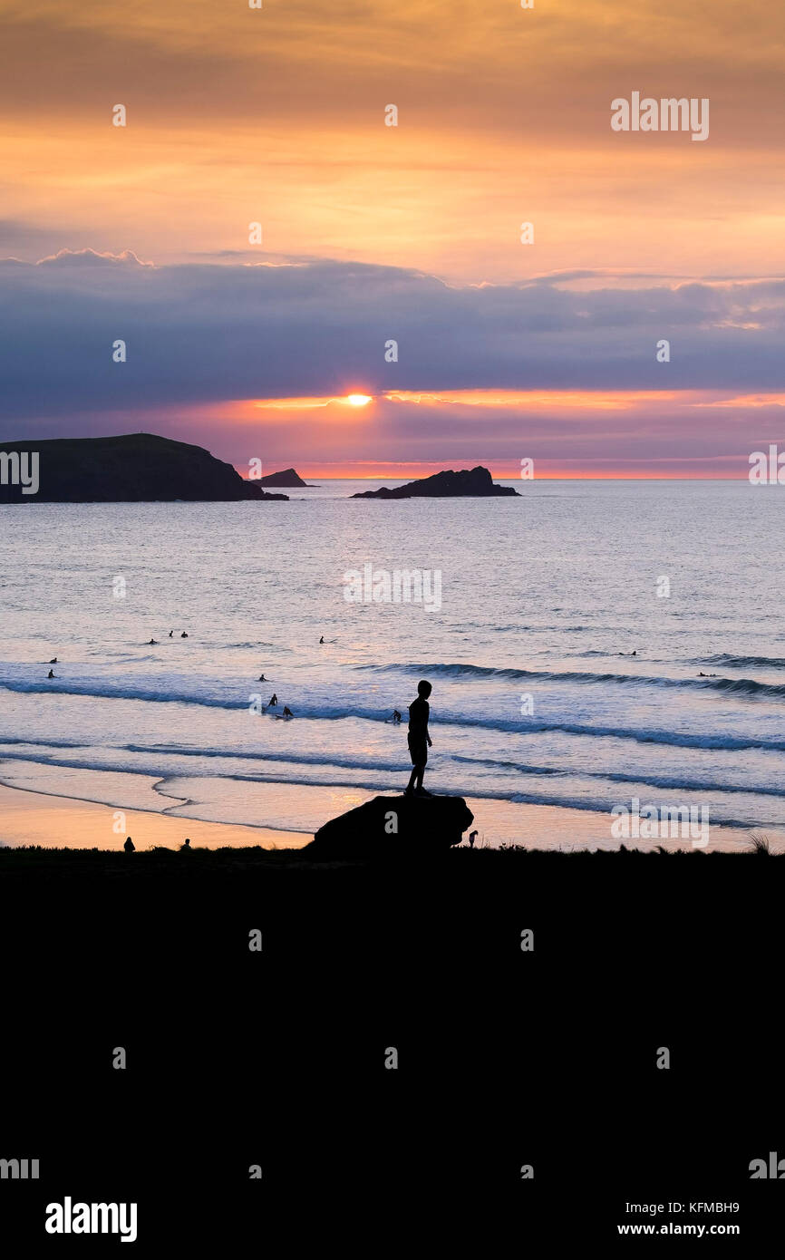 Spectacular sunset - people seen in silhouette as they watch the sun setting over Fistral in Newquay Cornwall. Stock Photo