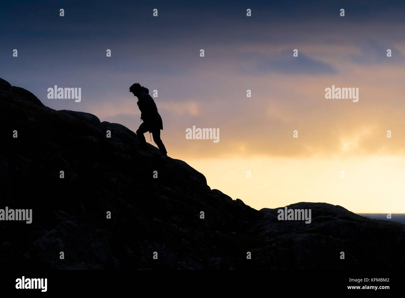 Silhouette - a solitary man silhouetted against evening light as he climbs a hill. Stock Photo