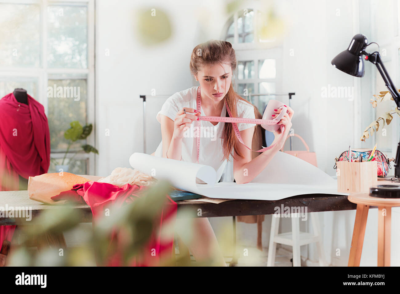 Fashion designers working in studio sitting on the desk Stock Photo - Alamy