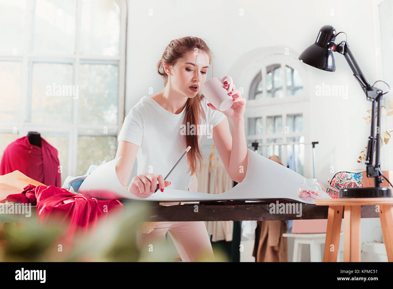 Fashion designers working in studio sitting on the desk Stock Photo - Alamy