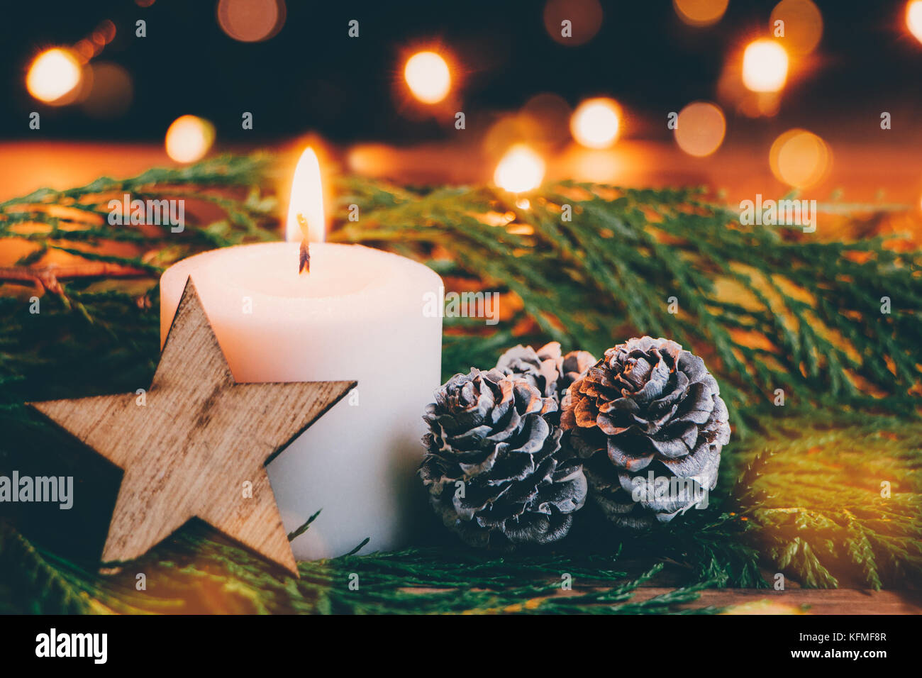 Christmas white candle with a wooden star, tree branches and pine cones ...