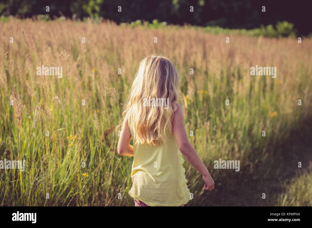 little blond girl walking in rural path among fields Stock Photo - Alamy