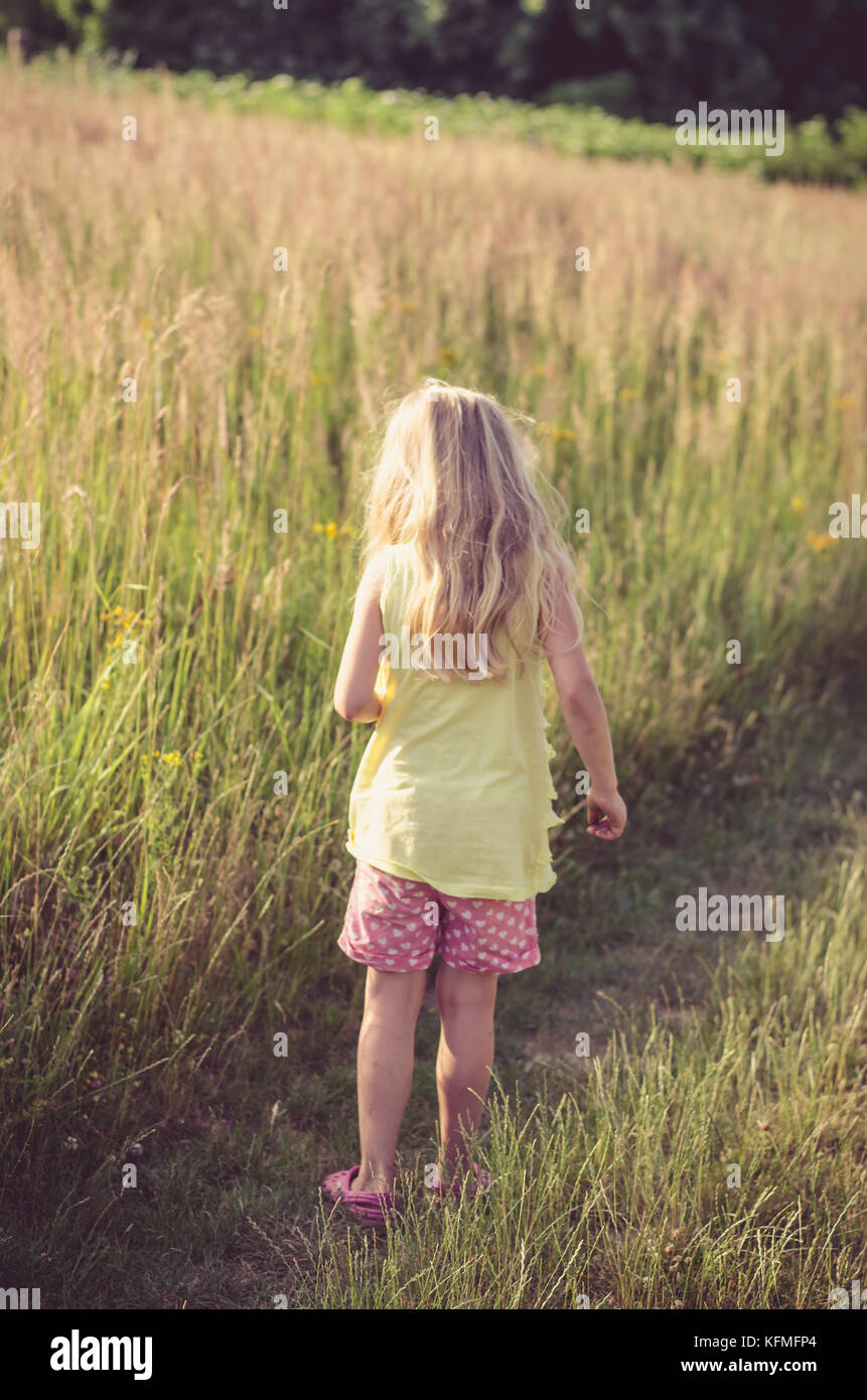 little blond girl walking in rural path among fields Stock Photo - Alamy