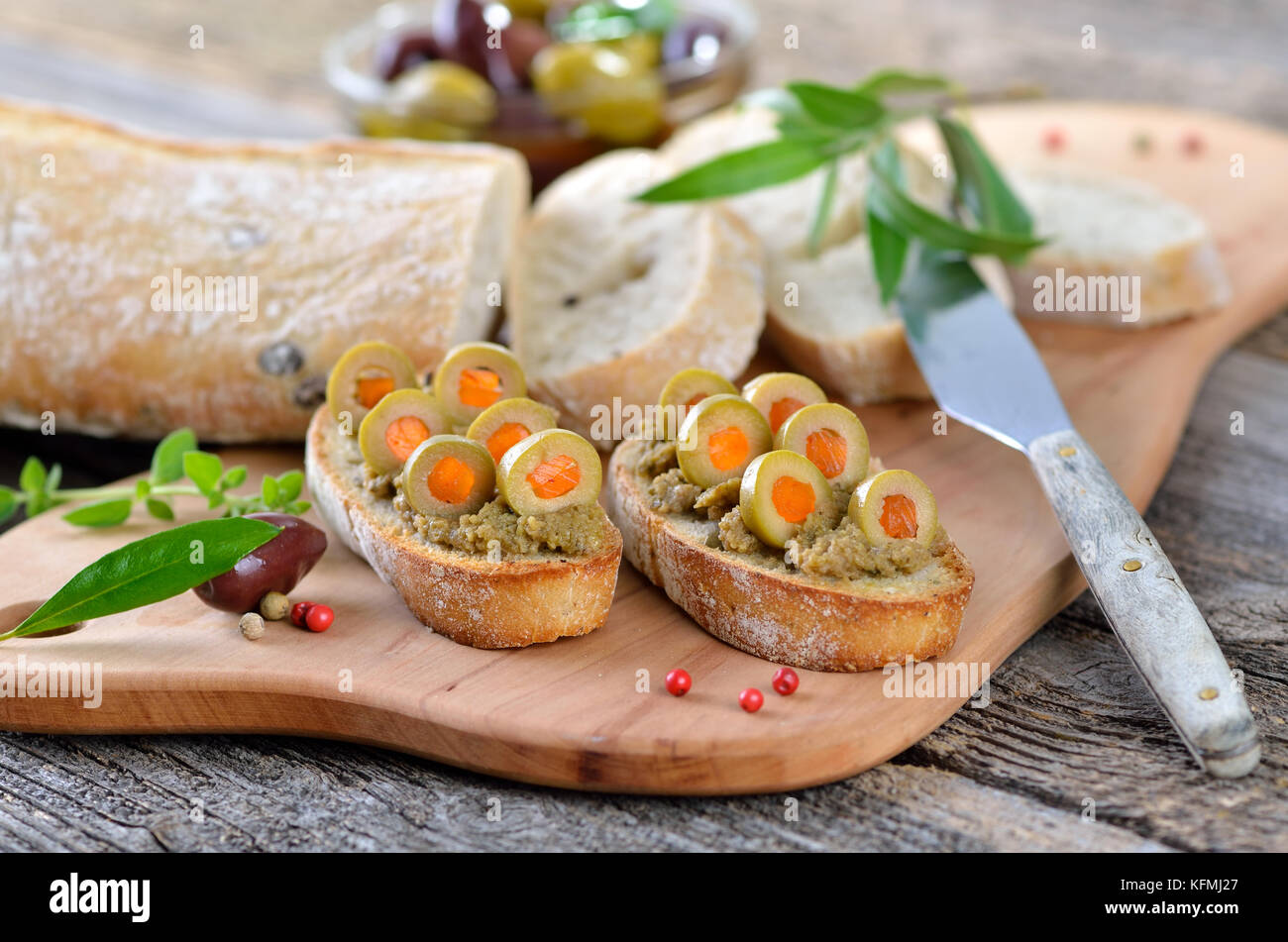 Olive paste on baked olive baguette, decorated with stuffed green
