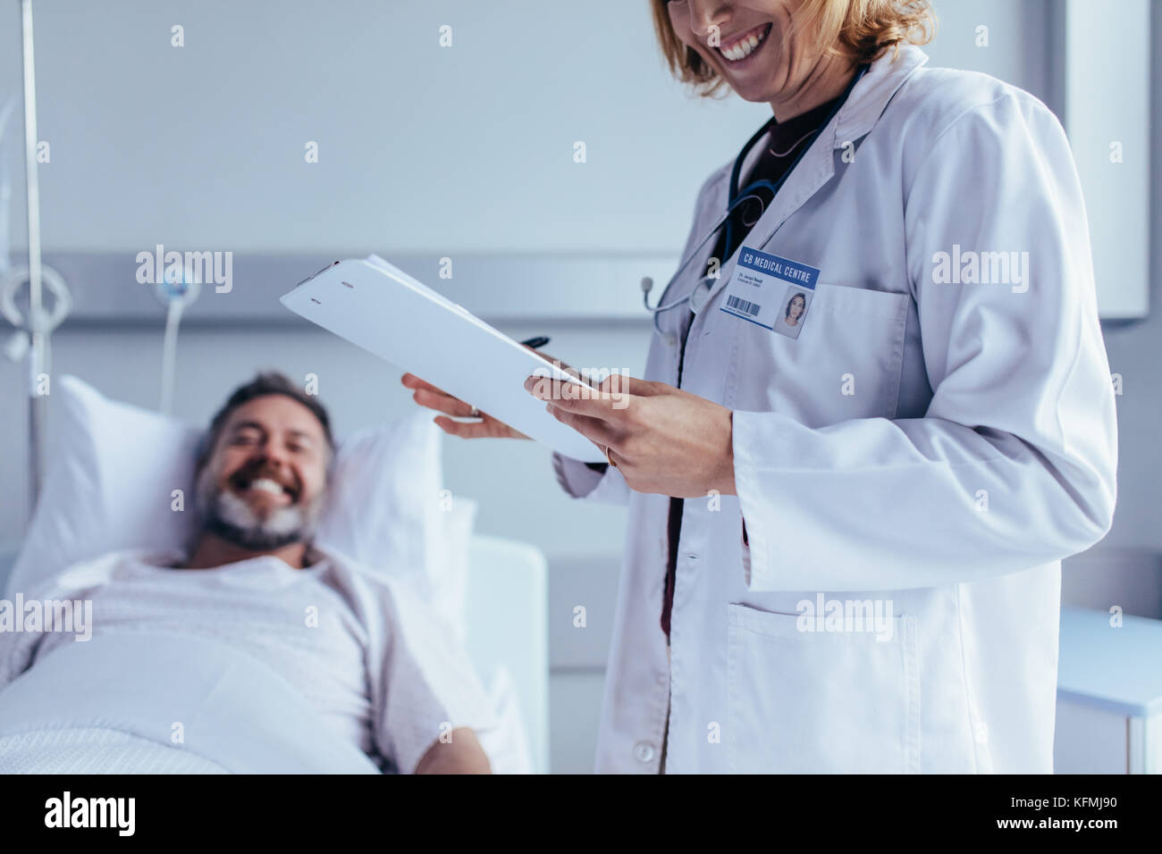 Healthcare worker with reports visiting male patient lying in bed