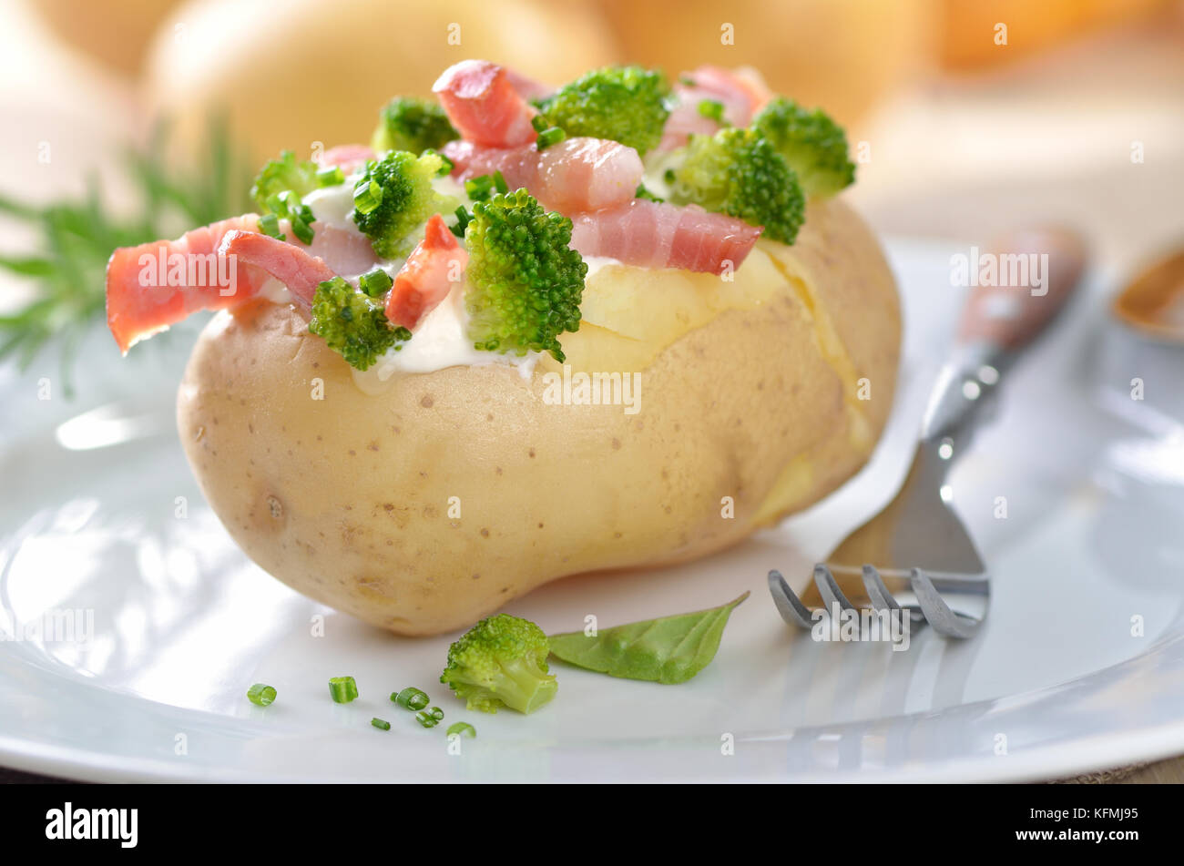 Baked potato stuffed with fried bacon strips, broccoli, chives and