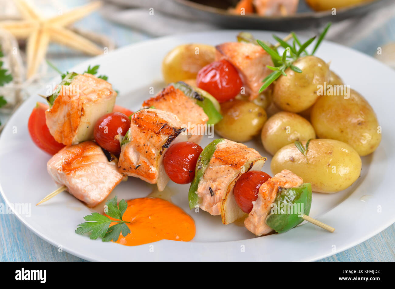 Fried salmon skewers with vegetables and small fried potatoes with