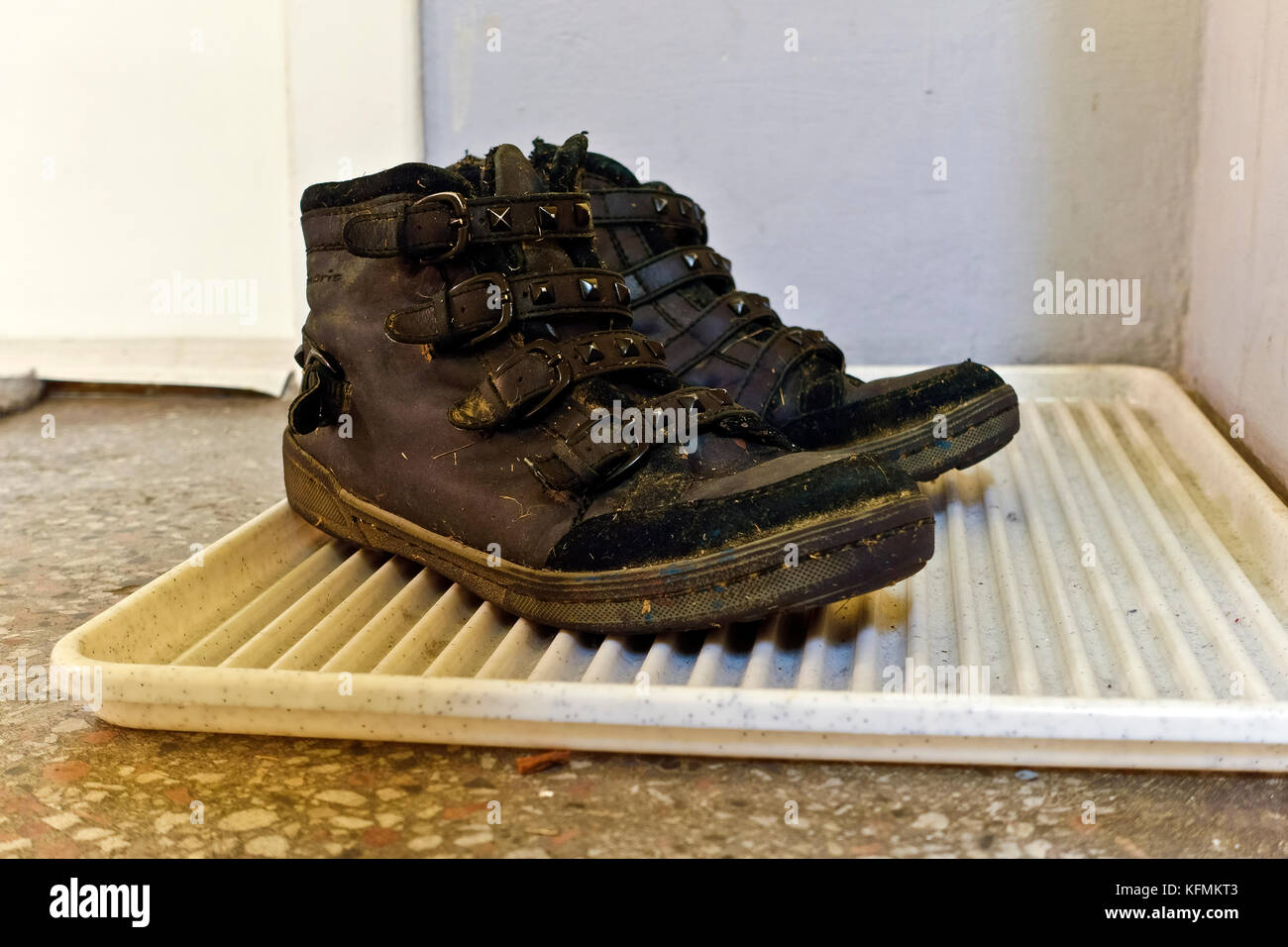 Dusty well worn hiking boots, on staircase in front of apartment door, in an old condominium socialist realism style in 1950s. Vienna, Austria, Europe Stock Photo