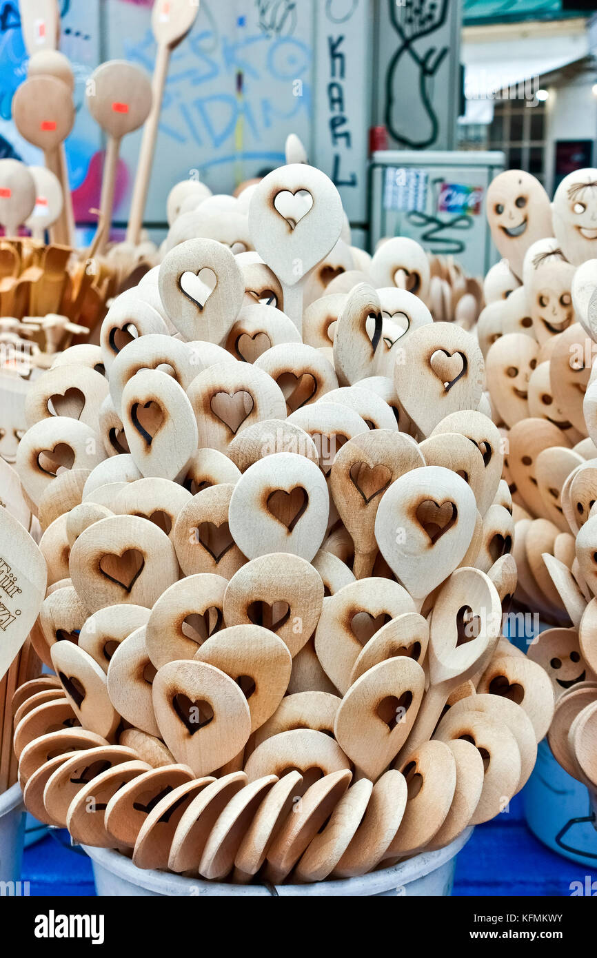 Wooden spoons with carved heart shape on display in a stall at the market. Stack of handcrafted organic cooking tools, close up, detail. Vienna. Stock Photo