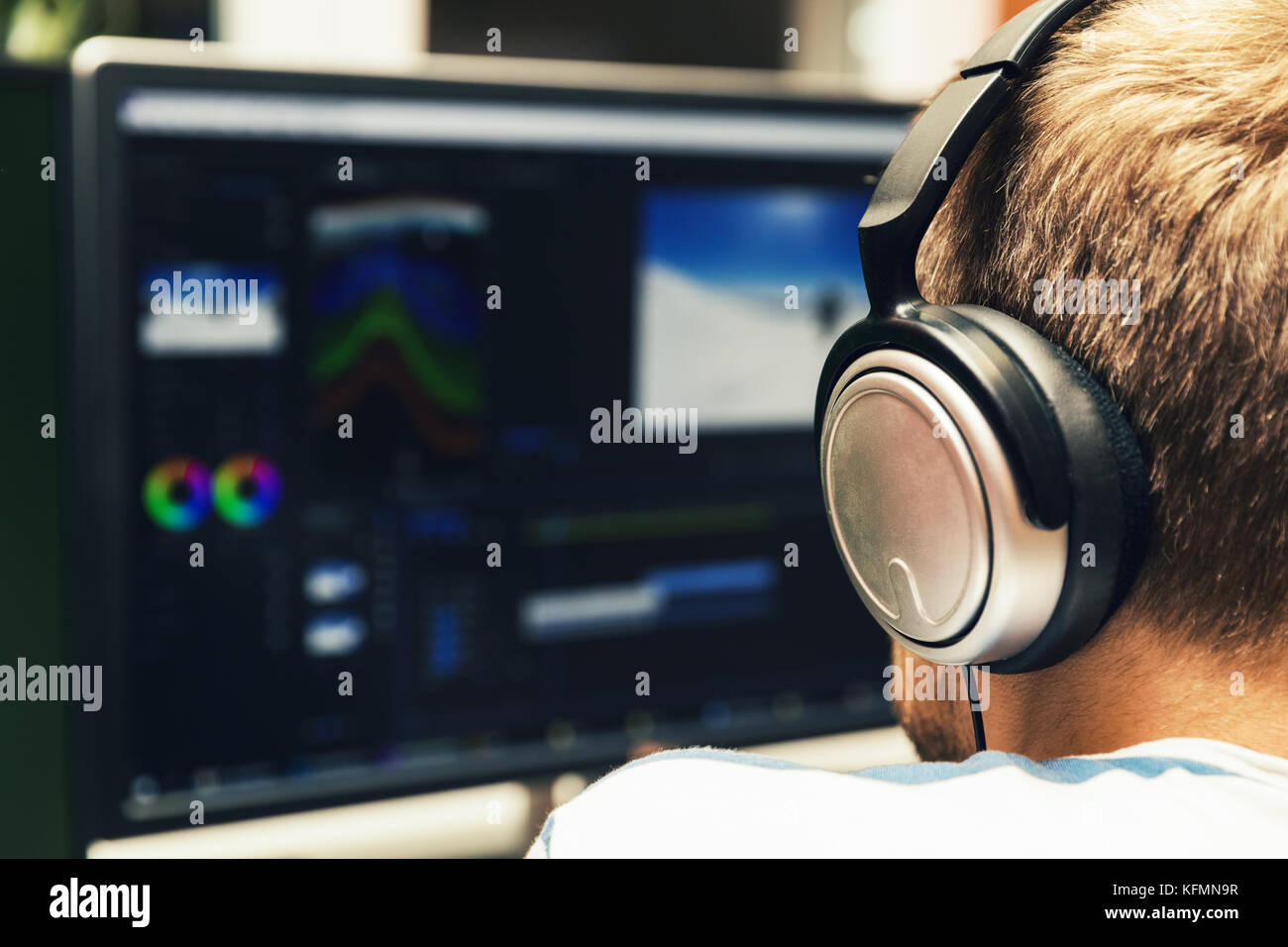 man doing video editing on computer with headphones on Stock Photo