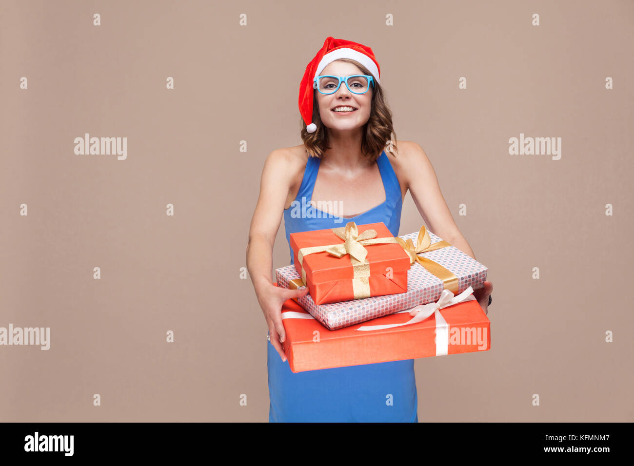 Its for you. Delivery woman holding a red box. Studio shot on brown background Stock Photo