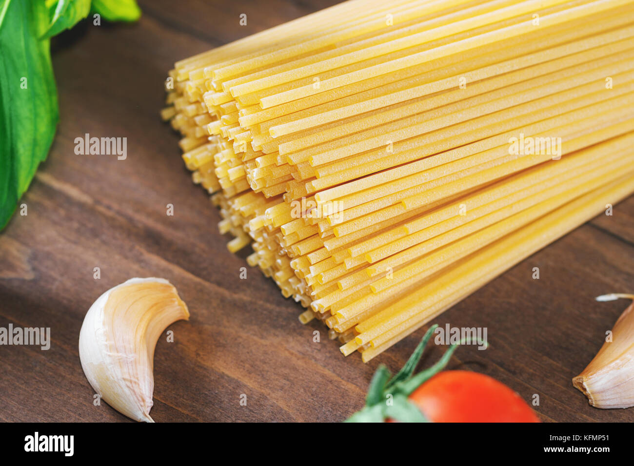 Cooking an Italian pasta. Uncooked spaghetti with fresh tomatoes, basil
