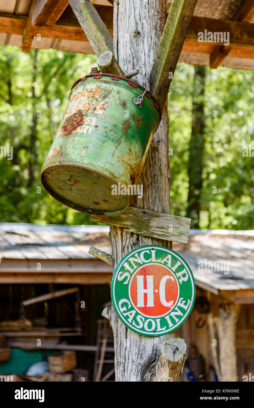 An old green antique gasoline can hangs next to a sign for Sinclair HC gasoline in rural Alabama, USA. Stock Photo