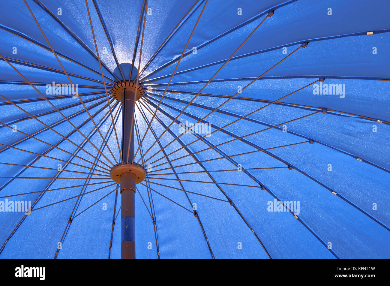 View from under the umbrella on a clear summer day. The sun shines through the garden umbrella. Stock Photo