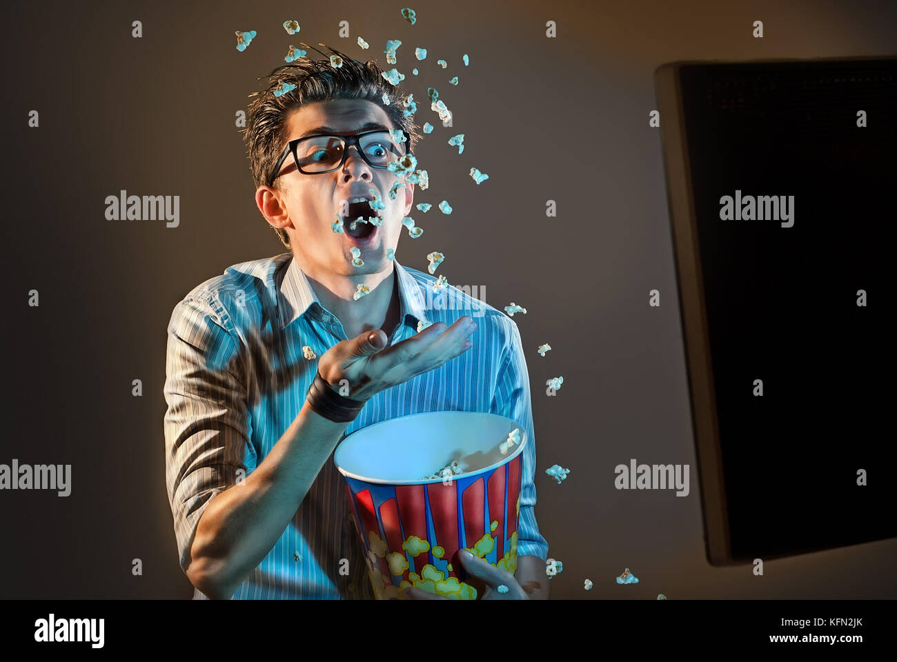A man watches the movie alone in the glasses and eats popcorn Stock Photo