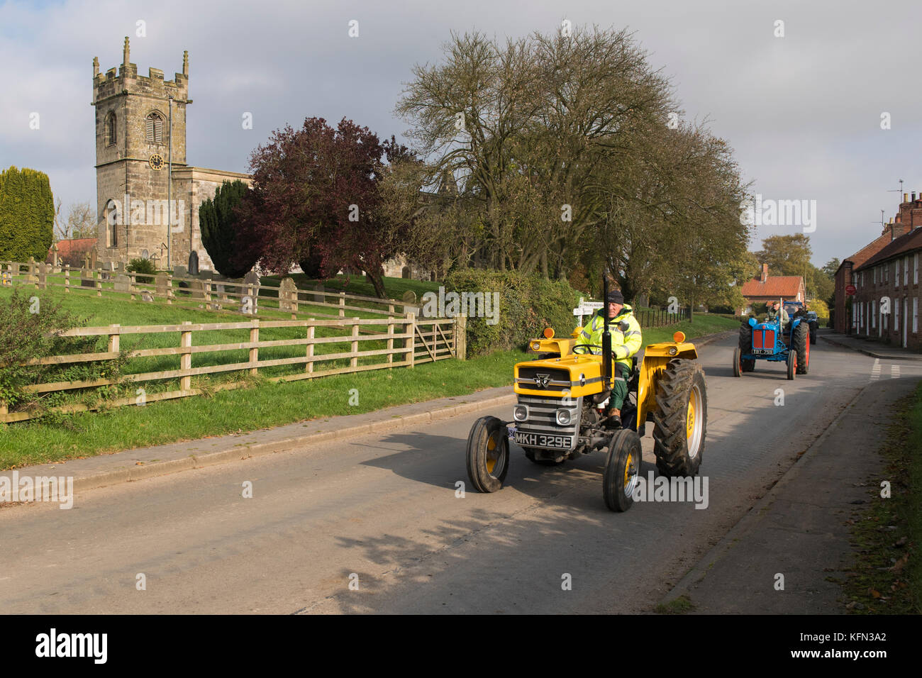 Man driving old yellow vintage MF tractor through Bugthorpe village on Wolds Vintage Group Road