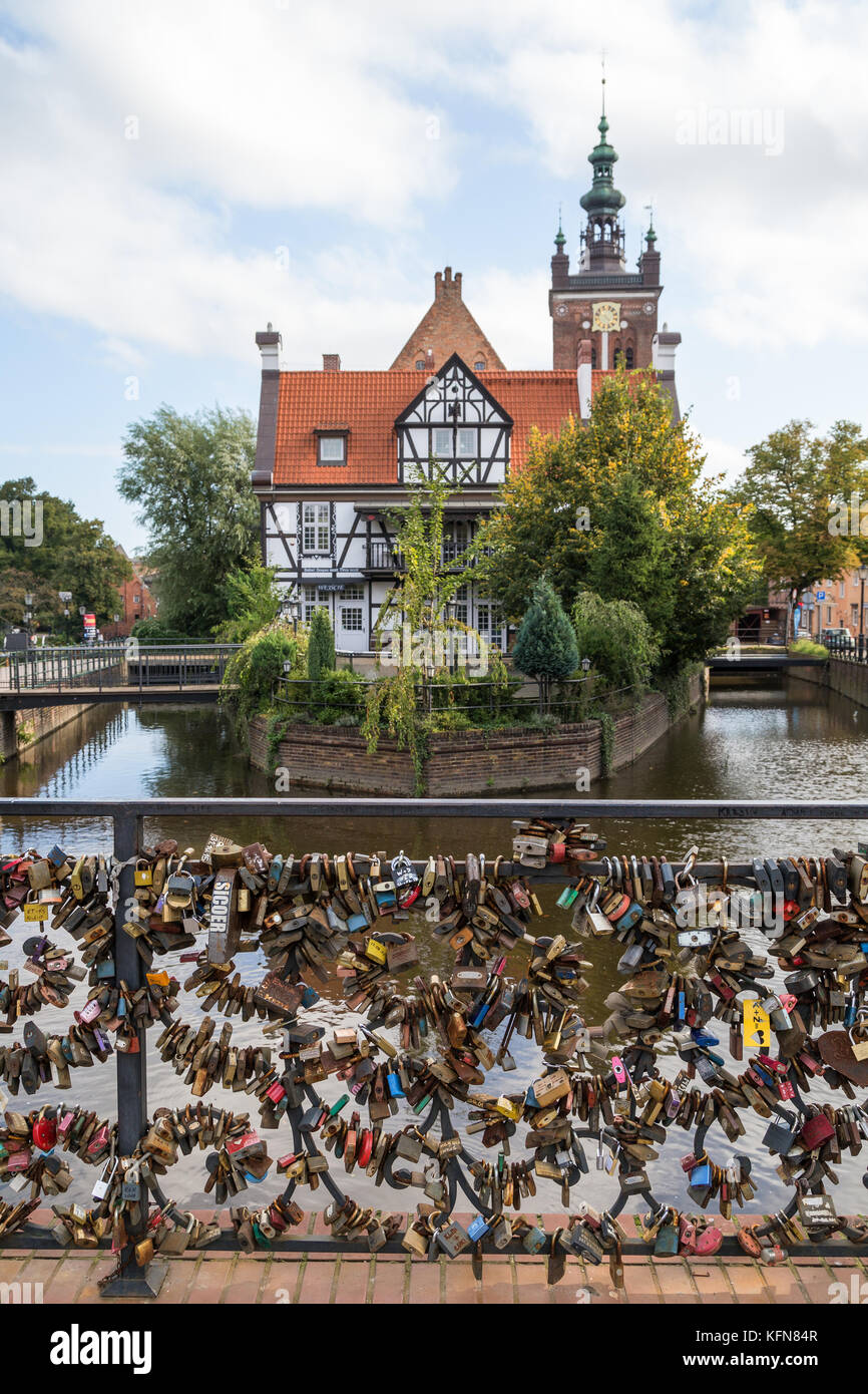 View of many love locks at the Love Bridge and Miller's House (Dom Mlynarza) at the Mill Island on Raduni Canal in Gdansk's Old Town in Poland. Stock Photo