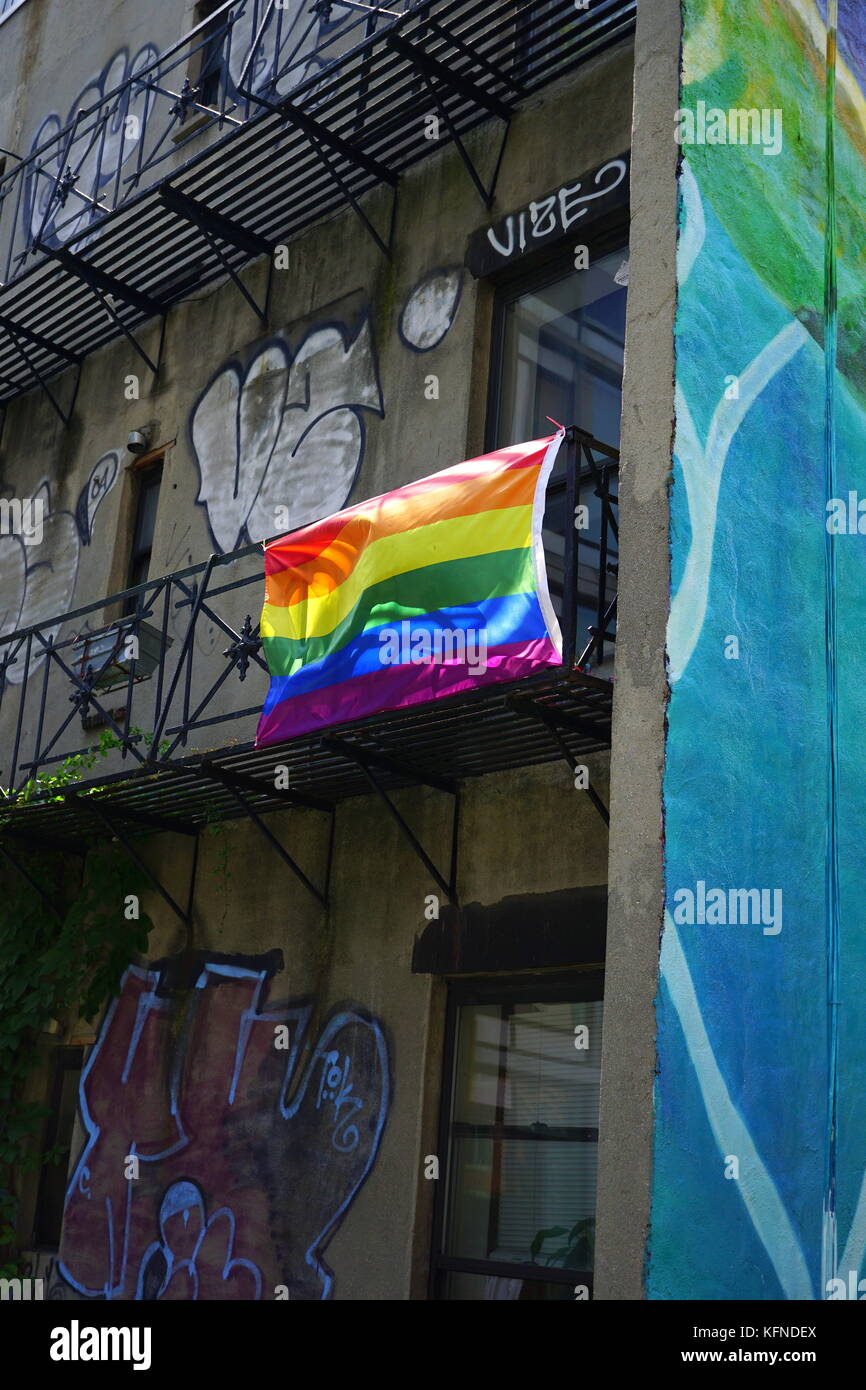 Gay pride flag (rainbow flag) hanging on the fire escape of an old apartment building, Chelsea, New York City, NY, USA Stock Photo
