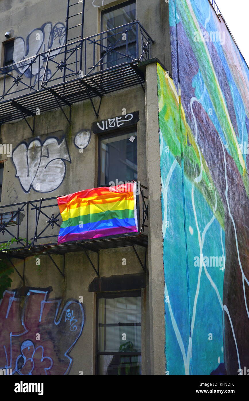 Gay pride flag (rainbow flag) hanging on the fire escape of an old apartment building, Chelsea, New York City, NY, USA Stock Photo