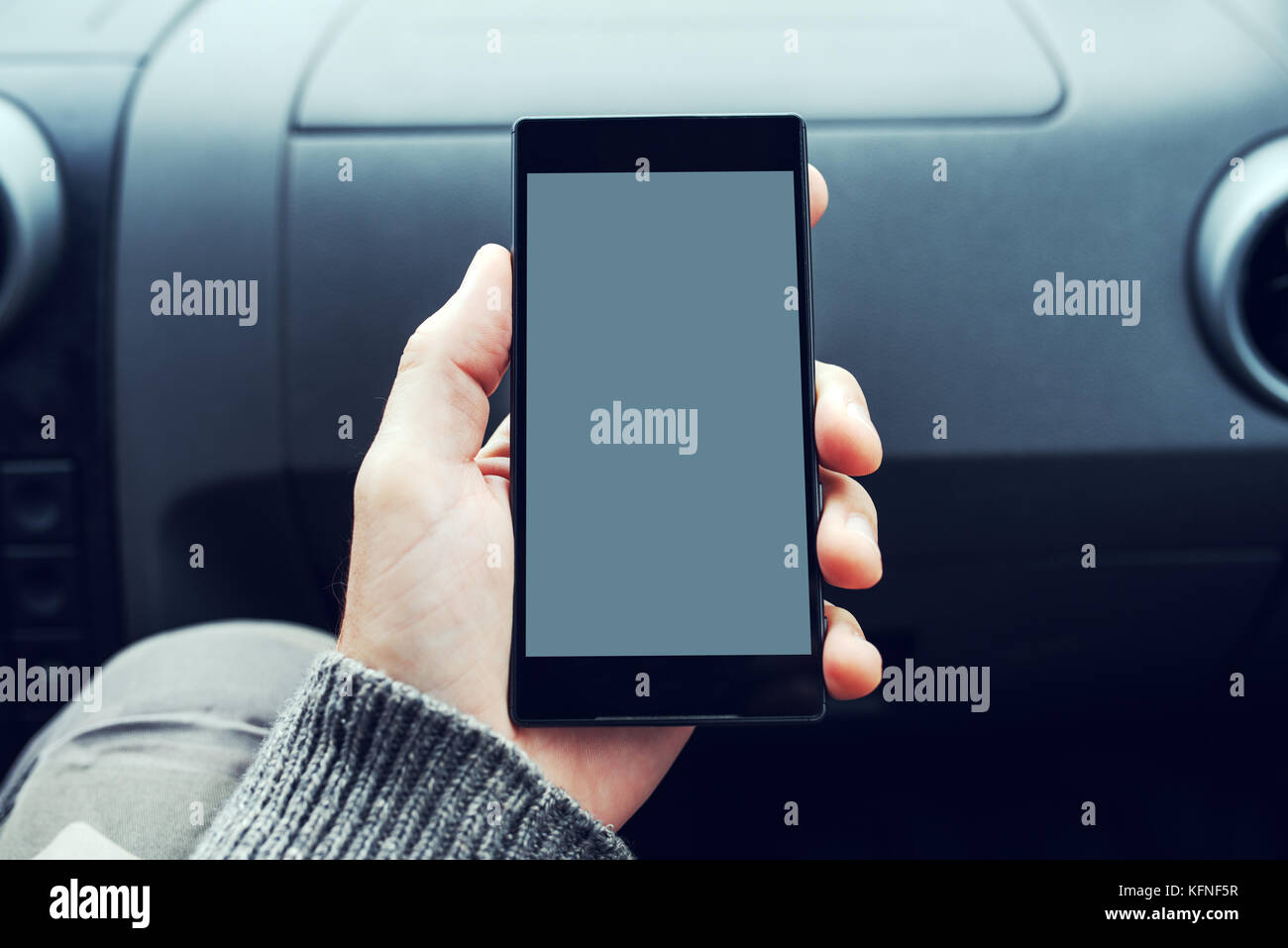 Man holding mobile phone with blank screen as copy space inside of the car. Image can be used as mock up for any vehicle, traffic or transportation re Stock Photo