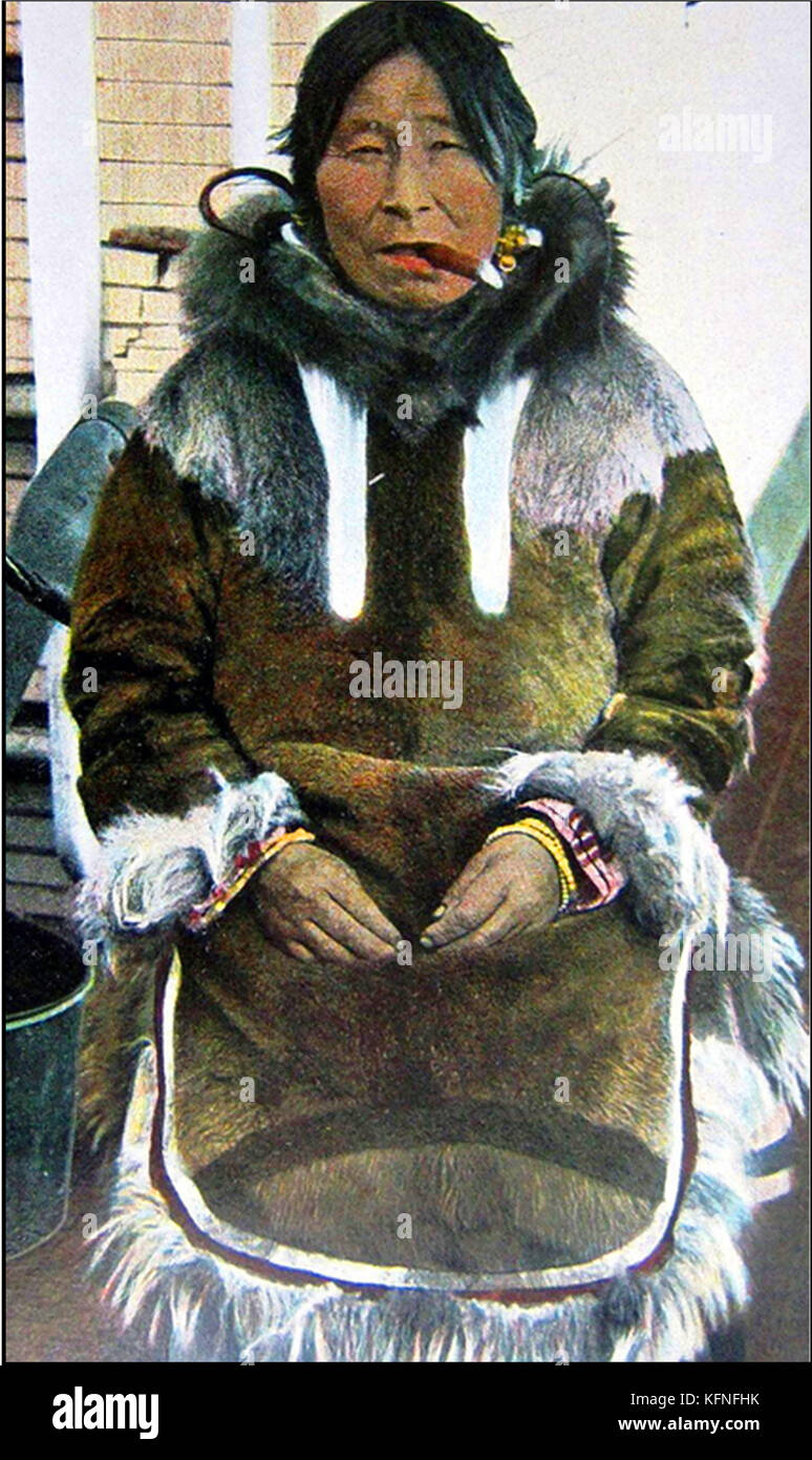 HISTORY OF TOBACCO - A 1910 image of an Inuit (Eskimo) woman smoking a cigar obtained by trading furs & fish. Stock Photo