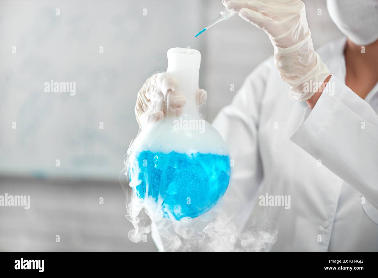 Cropped close up of a scientist in a labcoat and protective mask carrying out and experiment mixing chemicals at the laboratory copyspace profession o Stock Photo