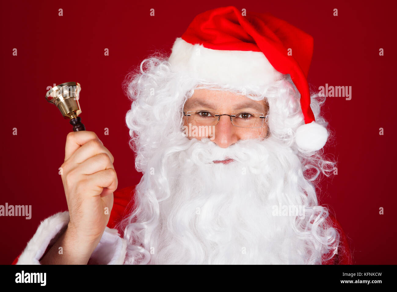 Close-up of santa holding bell over red background Stock Photo - Alamy