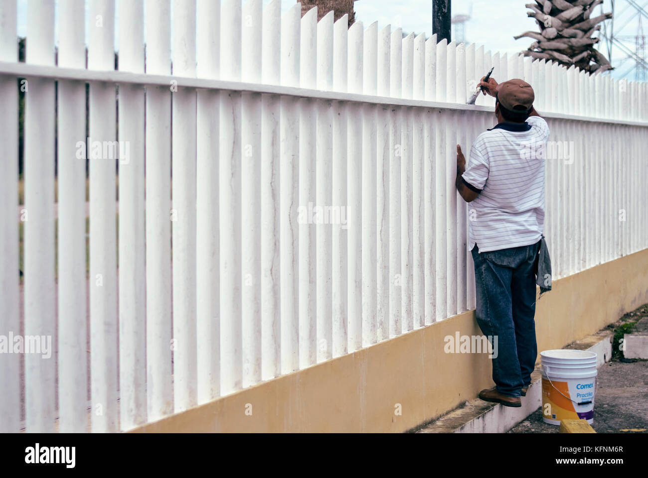 A worker does maintenance painting on a steel tube fence Stock Photo